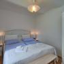 Comfortable bedroom with double bed, blue bed linen, bedside tables and a closet with mirror.