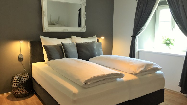 Modern bedroom with double bed, gray walls and decorative mirror.