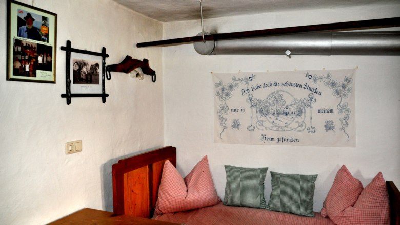 Interior view of a traditional room with wooden furniture, cushions and wall decorations in the Ablass farmhouse museum.