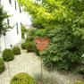 Garden with heart welcome sign and green bushes in front of a white building.