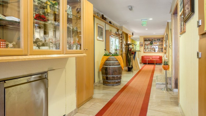A hotel corridor with red carpet, showcases and decorations.