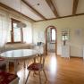 Dining area in a vacation home with wooden floor, white furniture and red upholstery.