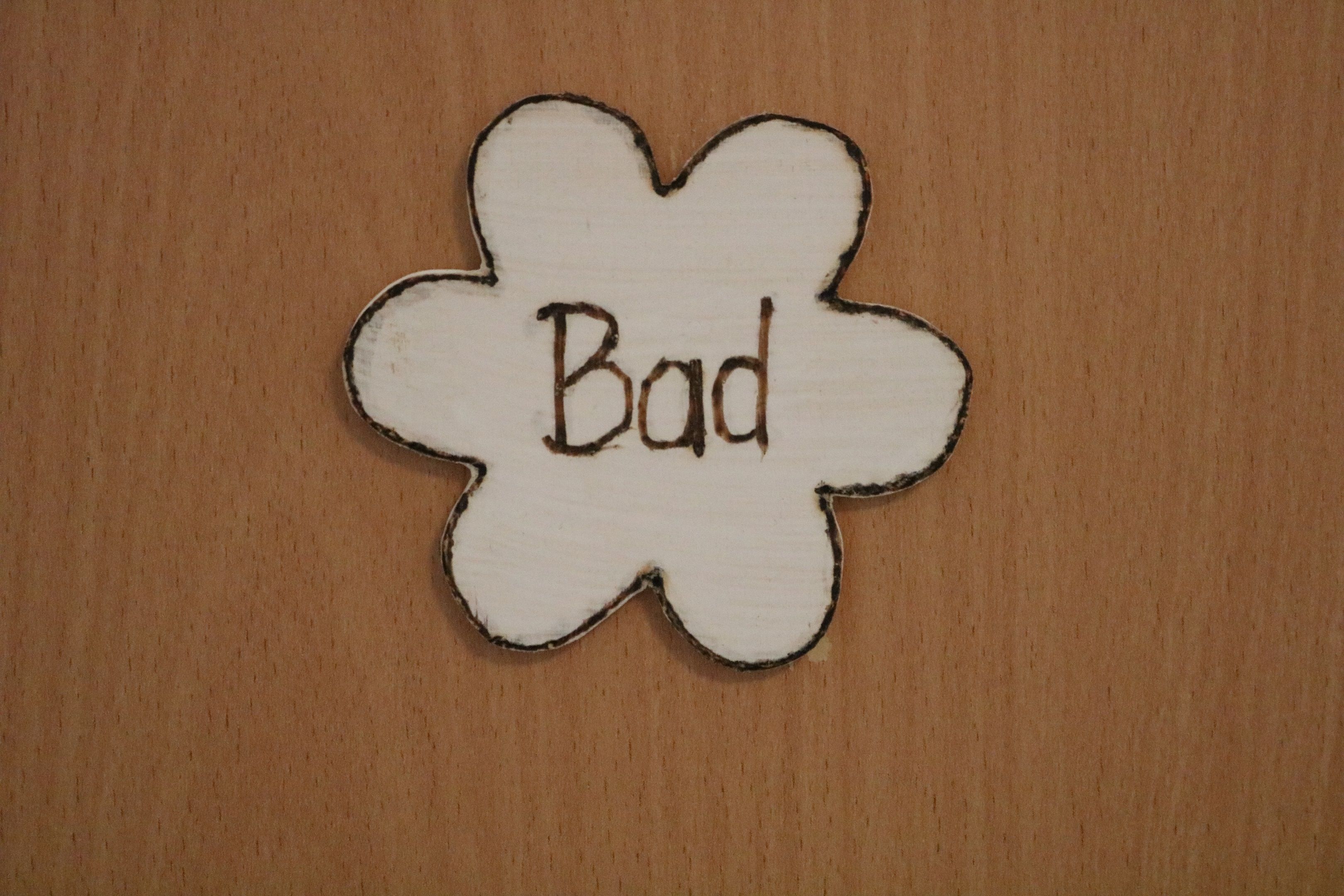 Wooden sign in the shape of a flower with the inscription 'Bad'.