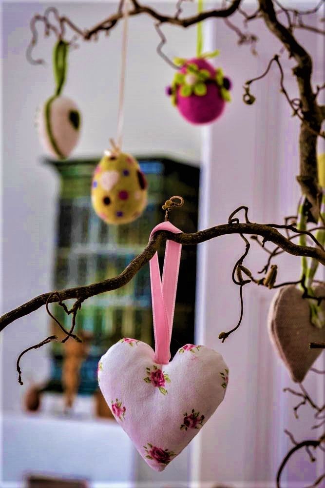 Decorative branch with hanging fabric hearts and colorful eggs.