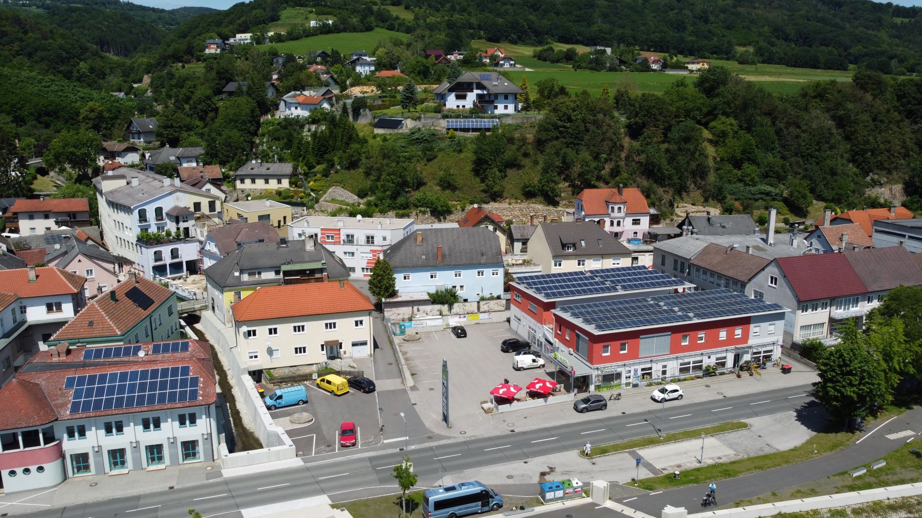 Aerial view of a village with buildings, streets and green landscape in the background.