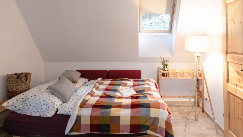 Cozy bedroom with bed, colorful blanket and reading lamp.