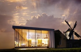 Modern glass architecture next to a traditional windmill at sunset.