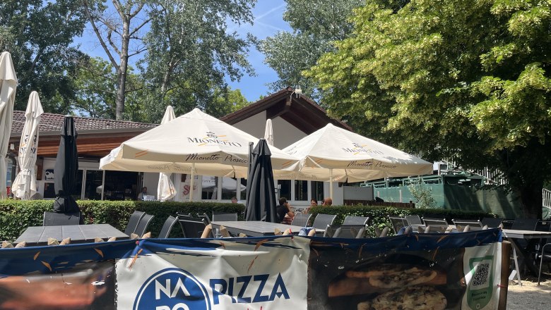 Guest garden with a view of the pizzeria building, trees in the background.