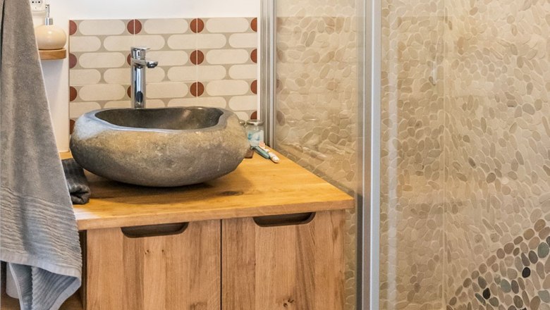 Modern bathroom with natural stone washbasin and wooden cabinet.