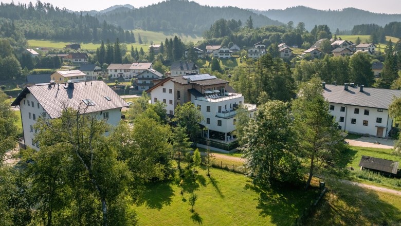 Aerial view of buildings in a green, hilly landscape.