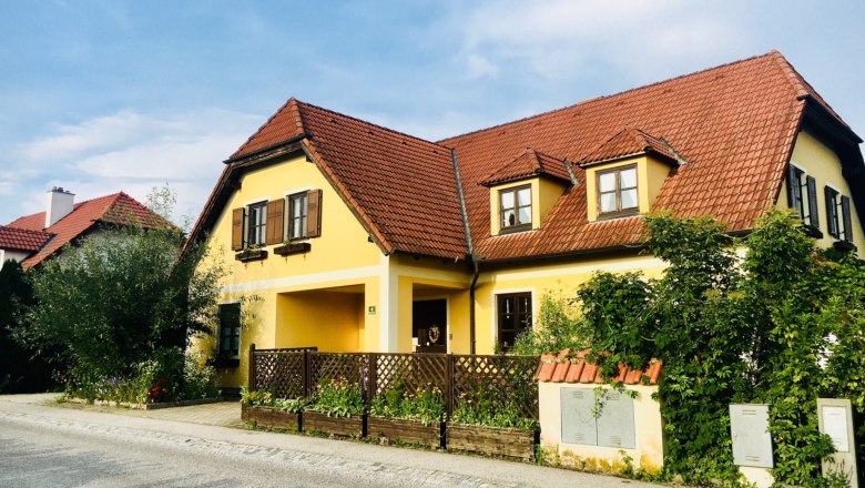 Yellow country house with red tiled roof and garden.