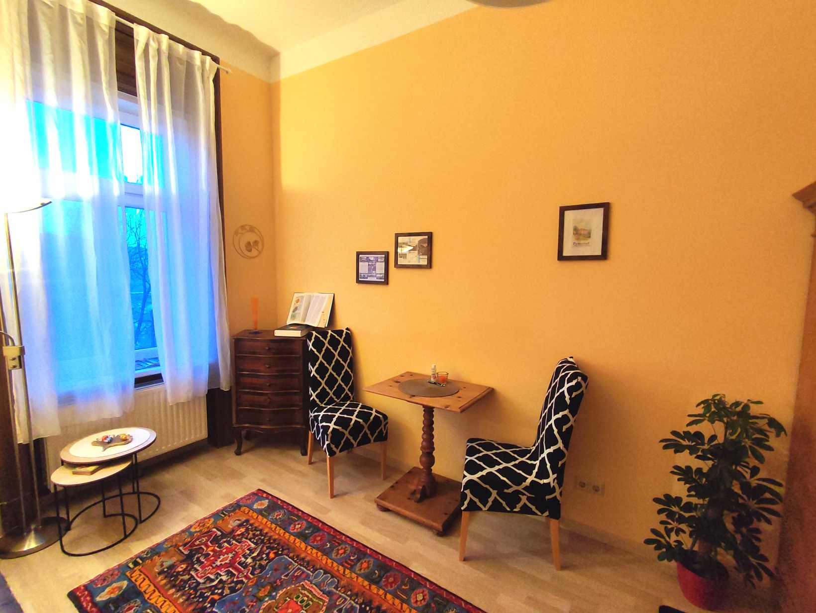 Cozy room with two chairs, small table, carpet and plants.