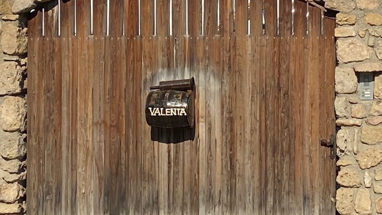 Wooden gate with letterbox and inscription 'Valenta'.