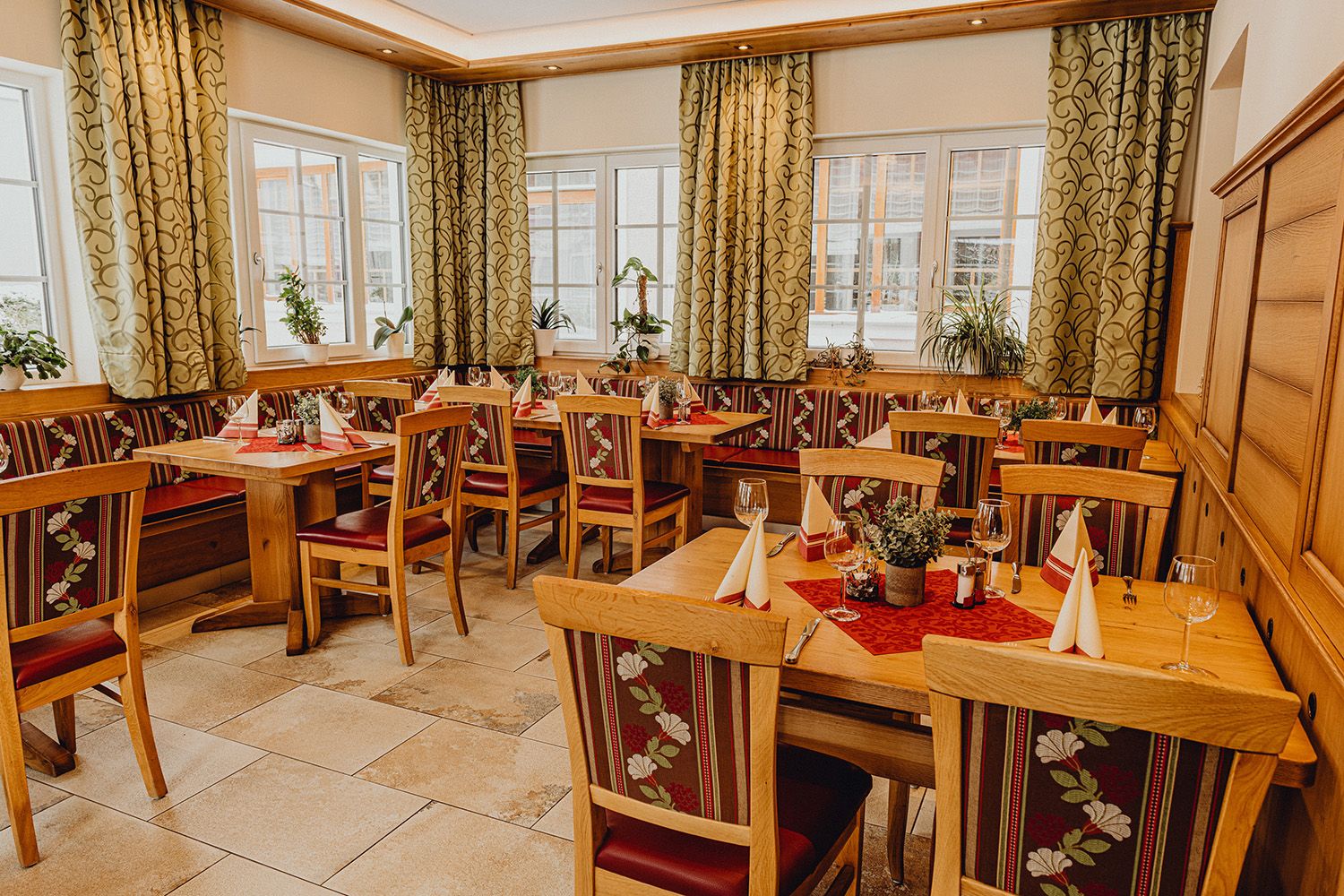 Cozy restaurant with wooden furniture, decorated tables and plants by the window.