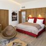 Modern hotel room with red bed, wooden furniture and golf magazines on the table.