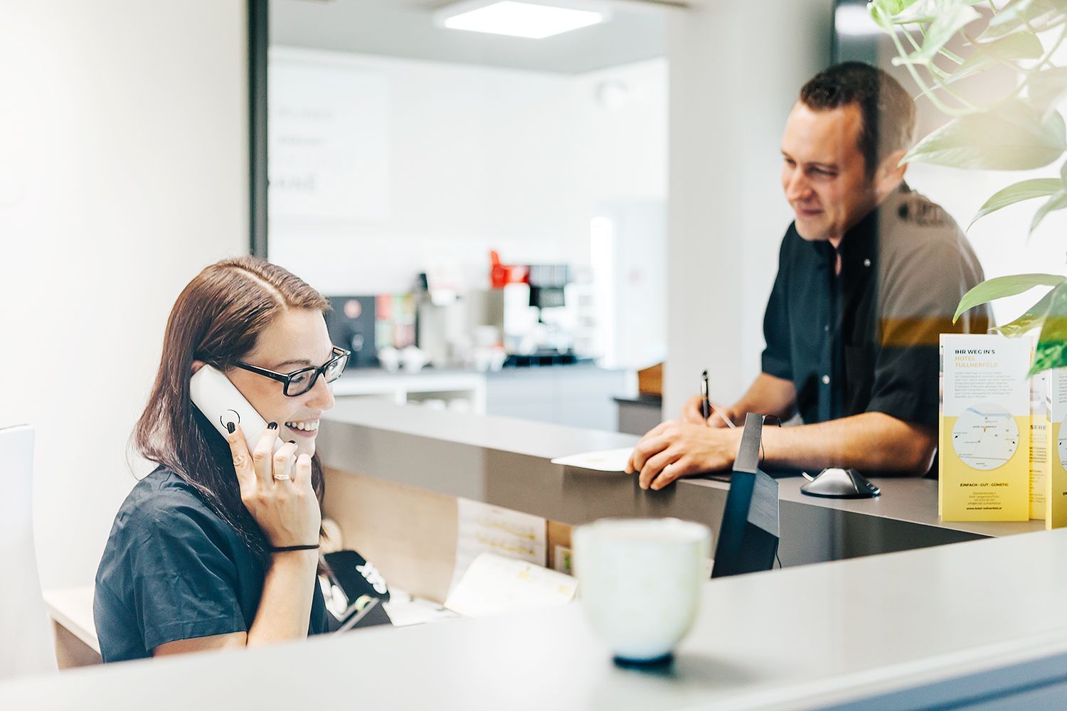 Receptionist on the phone with a guest at reception.