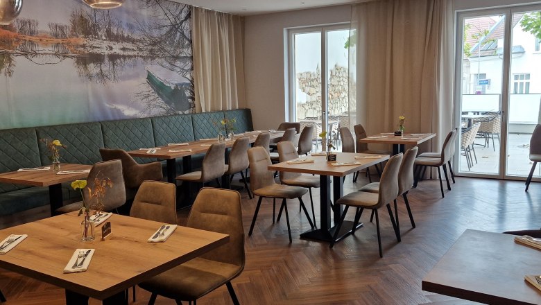 Interior view of a modern restaurant with wooden floor, tables and chairs.