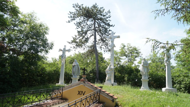 Station of the Cross with several white statues and a cross outside.
