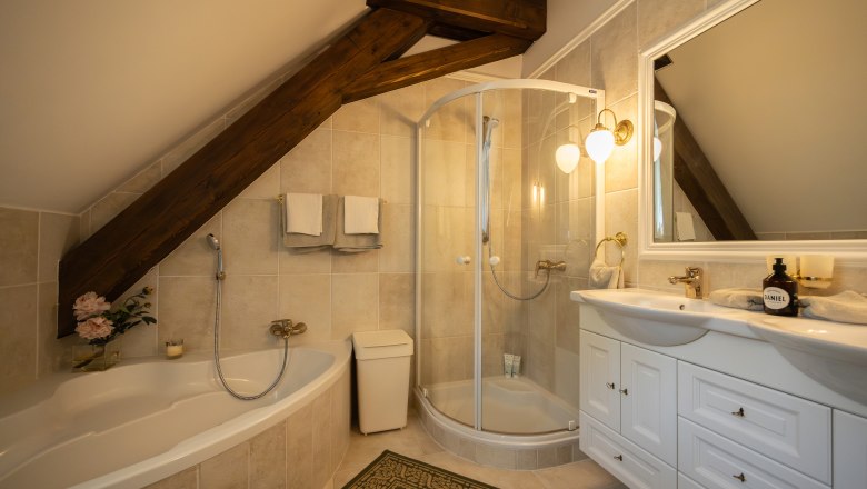 An elegant bathroom with bathtub, shower and washbasin under a sloping roof.