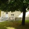 Inner courtyard with lawn, a tree and white plastic chairs. The yellow building in the background.