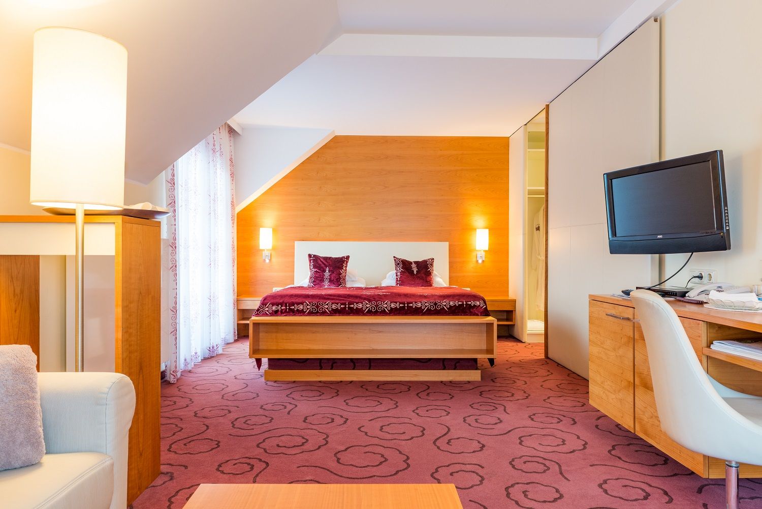 Hotel room with double bed, desk and TV.