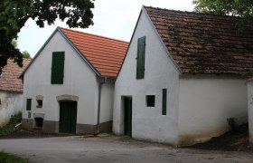 Two traditional wine cellars with white walls and red tiled roofs in a wine cellar lane.