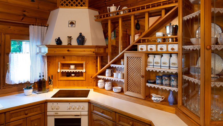 Rustic wooden kitchen with shelves, crockery and spice containers.