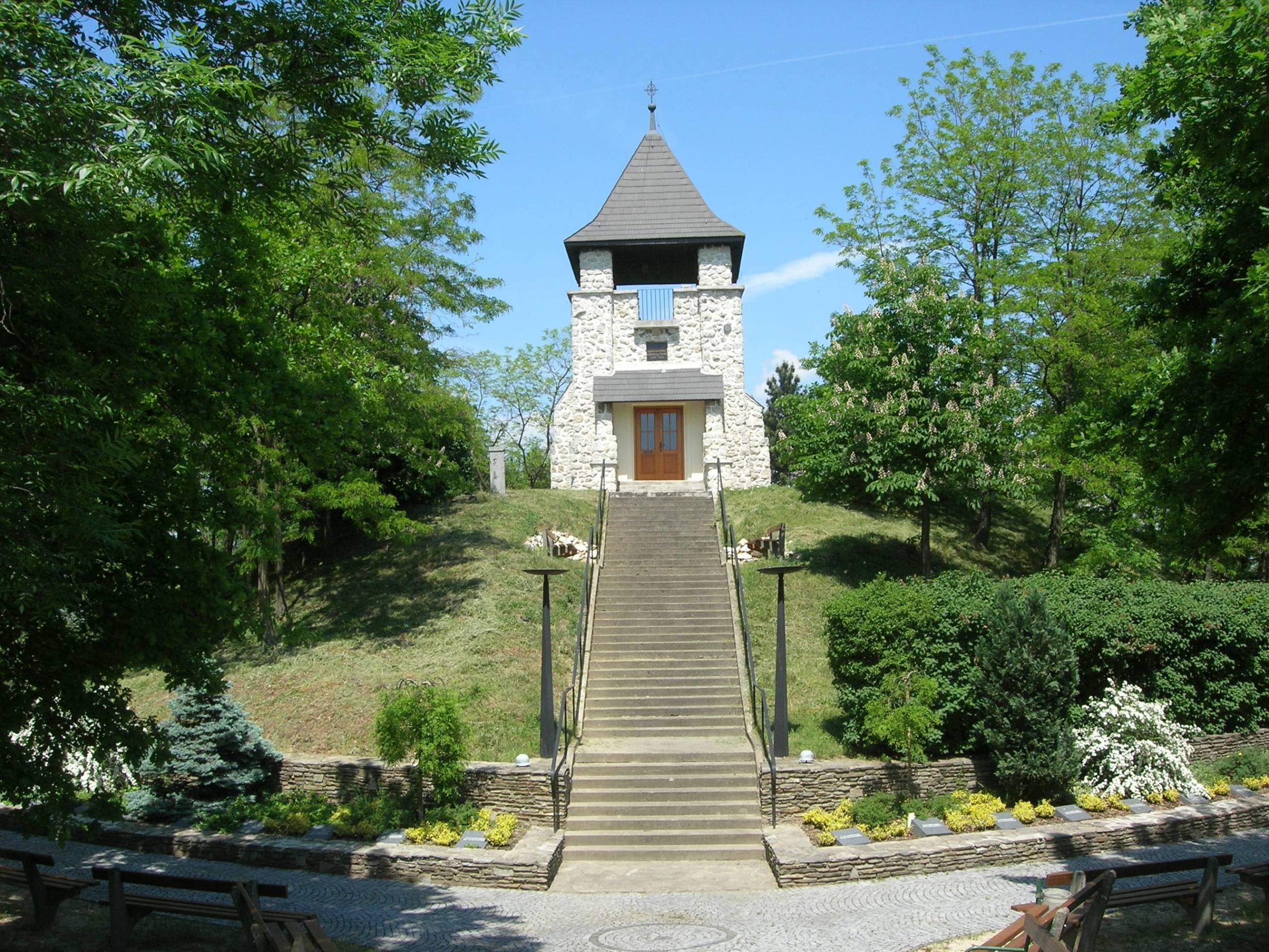 Stone tower on a hill with stairs and green surroundings.