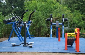 Outdoor fitness equipment on blue outdoor floor tiles.