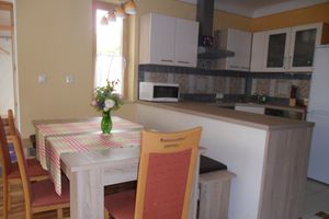 A modern kitchen and dining area with table, chairs and kitchen appliances.