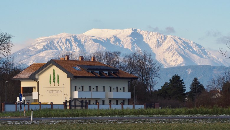 Exterior view Schneebergblick, © Mattone GmbH Building with the inscription 'mattone apartments' in front of a snow-covered mountain in the background.