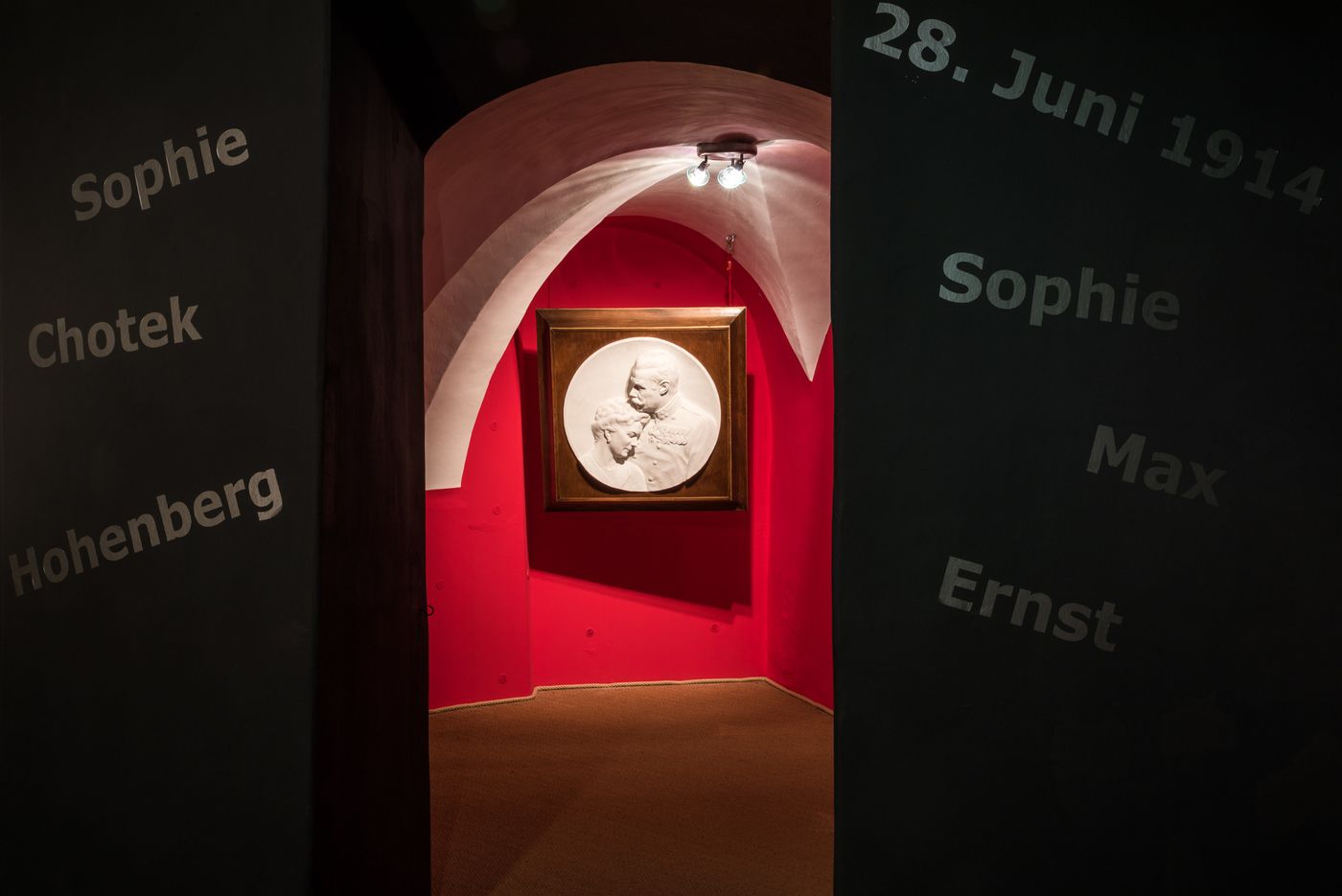 Entrance area of a museum with red background and relief portrait.