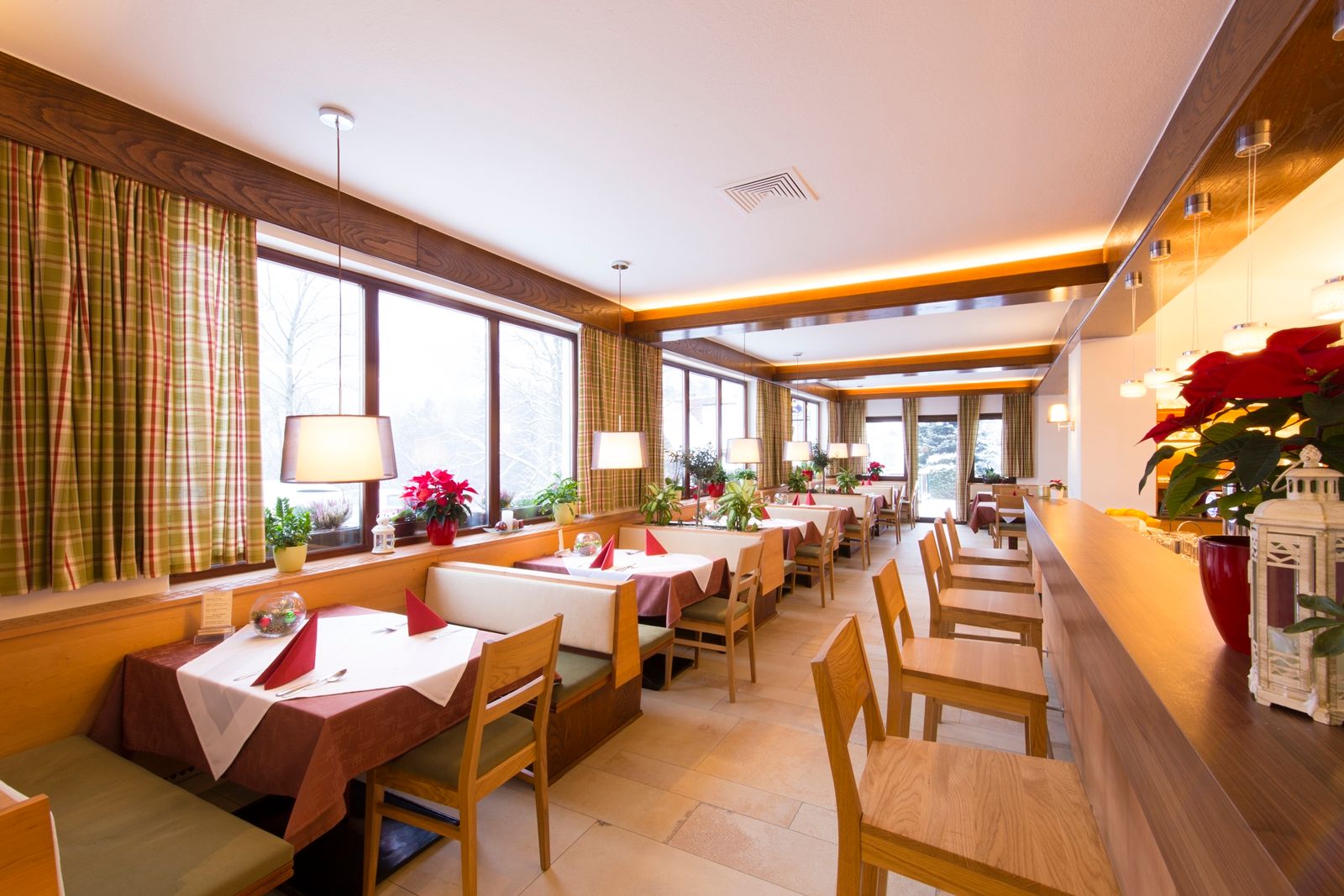 Interior view of a cozy restaurant with wooden furniture and large windows.