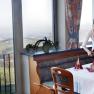 A woman sets a table in a restaurant with a view of a rural landscape.