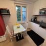 Small kitchen with red fridge, table, chairs and kitchenette.
