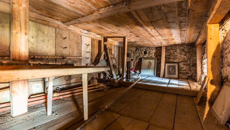 Interior view of the upper floor of the Lichtenegg fortified church with wooden beams and old, dusty pictures.