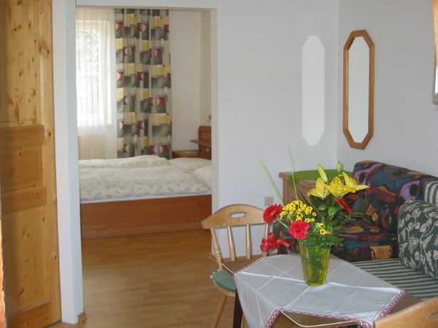 Living room with table, bouquet of flowers and view into the bedroom.