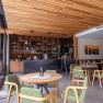 Interior view of the wine lounge with wooden elements, green chairs and a bar in the background.
