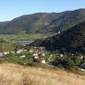 Panorama with wine glass in the foreground, view of a valley with villages and vineyards, surrounded by wooded hills.