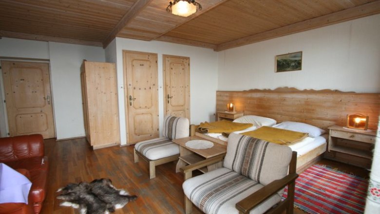 Cozy double room with wooden furniture, double bed, armchairs and carpet.