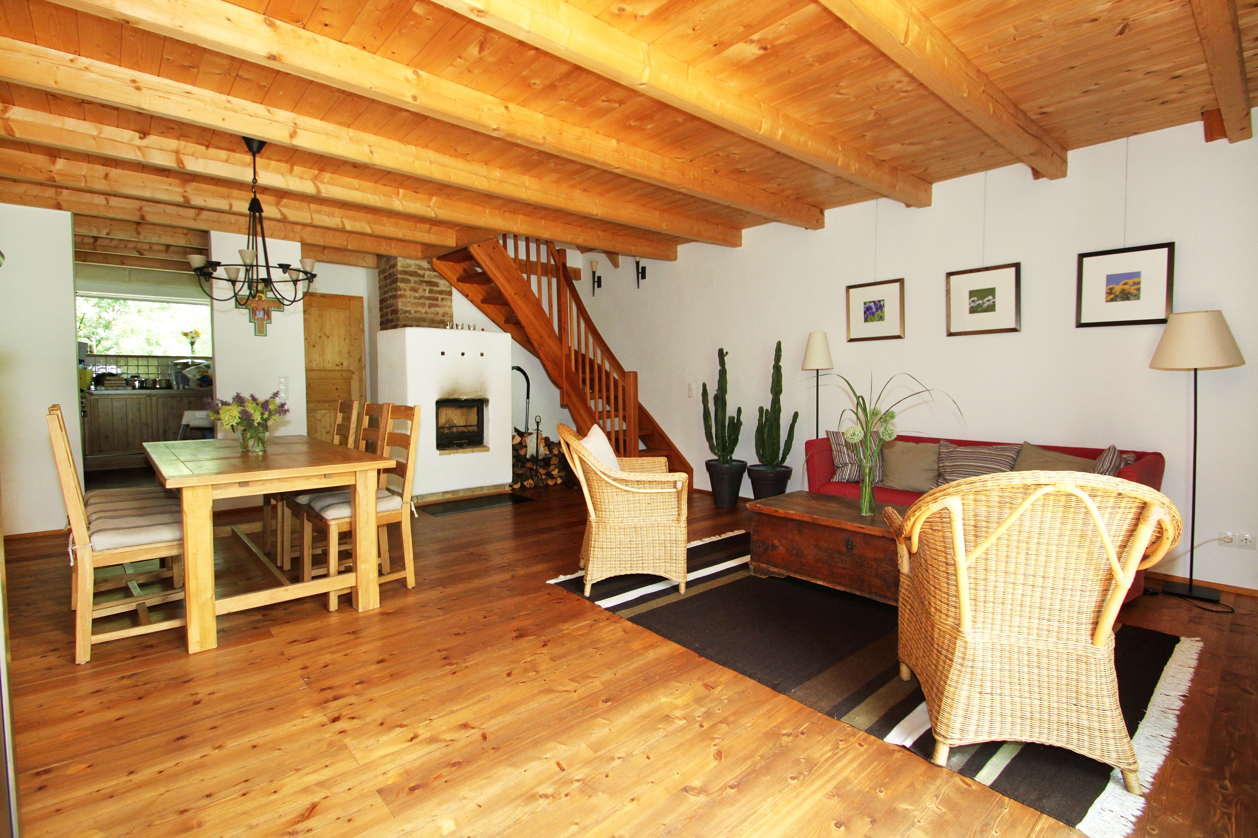 Cozy living room with wooden floor, dining table, fireplace, staircase and plants.