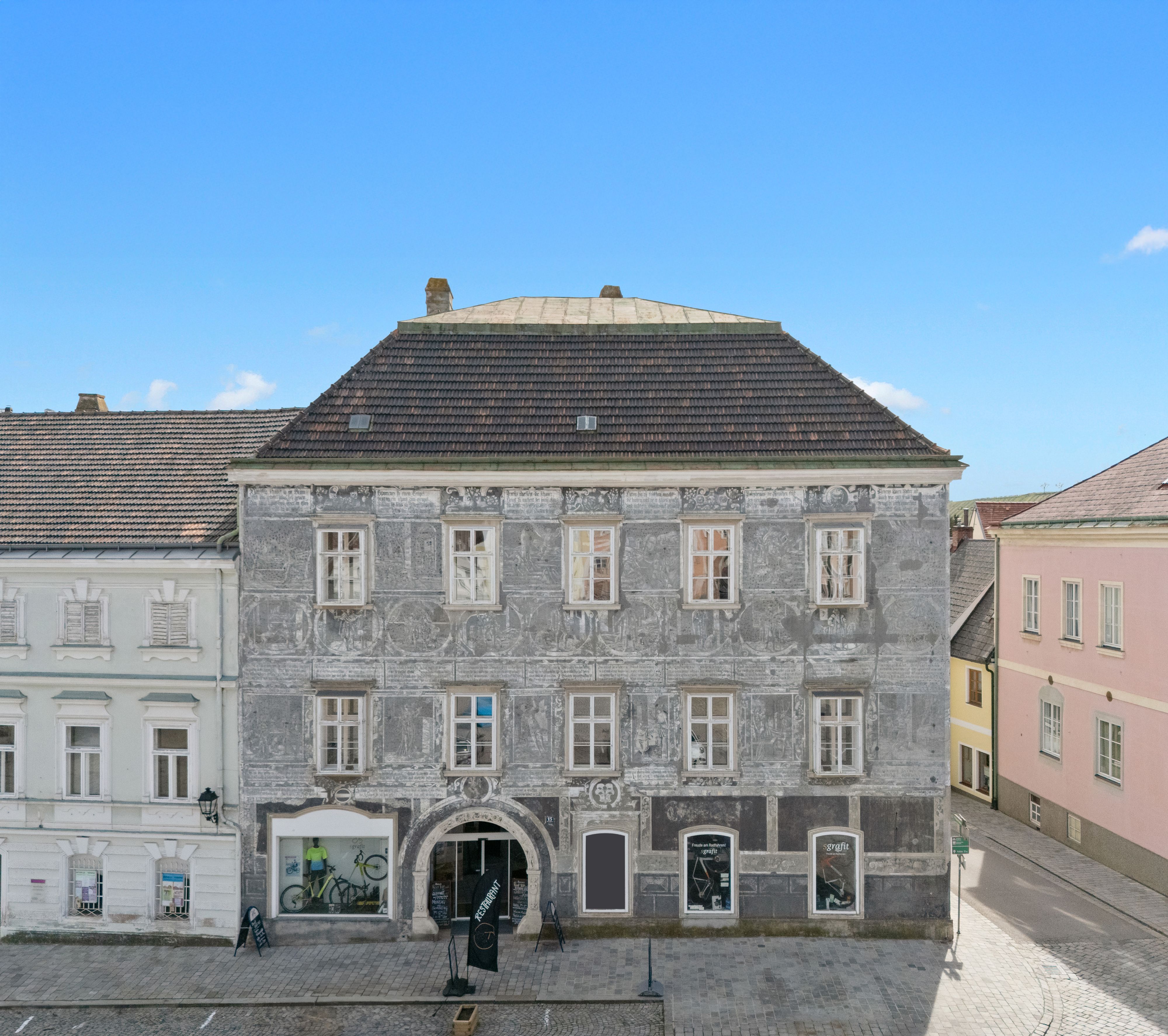 Historic building with a gray façade and decorative paintings in a town.