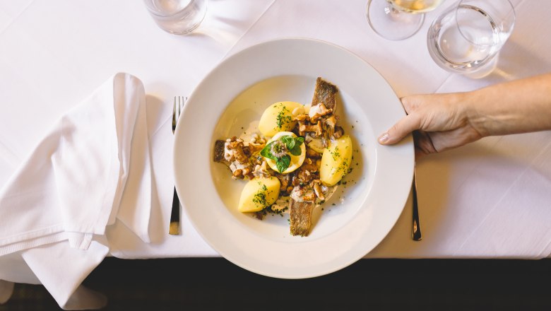 A plate of carp, potatoes and mushrooms on a white table.