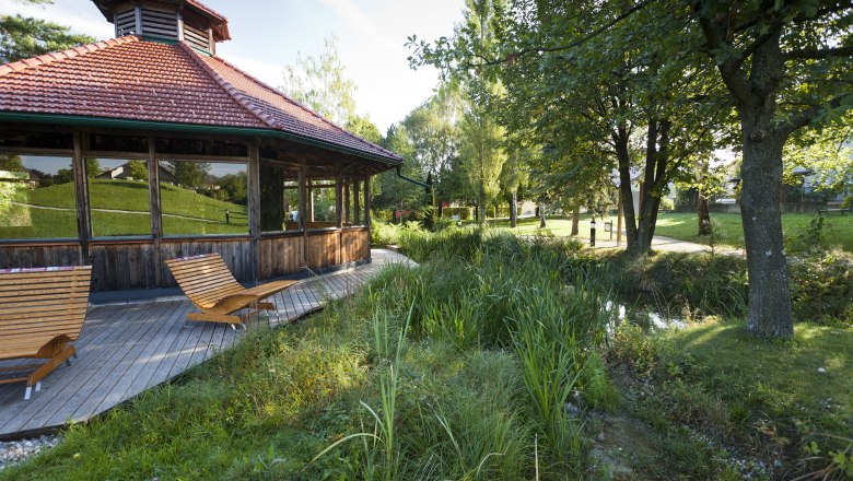 Wooden pavilion with deckchairs in a green park.