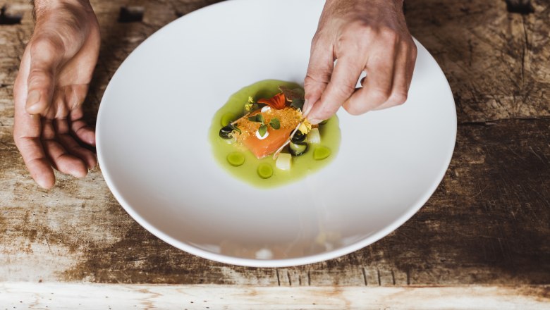 A plate of marinated fish and caviar, decorated with green sauce and herbs.