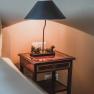 Bedside table with lamp and dog sculptures in a double room.