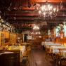 Interior view of a traditional inn with wooden furniture and decorative objects on the ceiling.