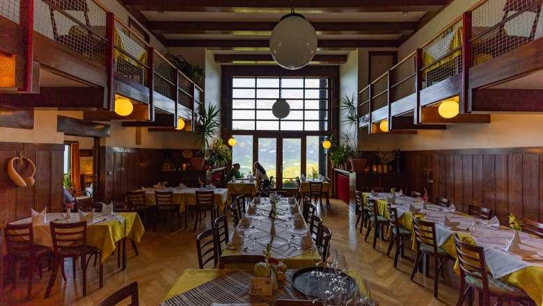 Interior view of a restaurant with wooden furniture and large windows.