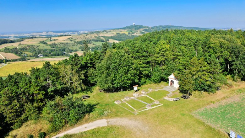 Landscape view from a lookout tower with forests, fields and a small chapel.