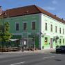 Green building with hotel and café signs on a street corner.